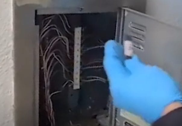 A police officer removes a hidden bag of methamphetamine from an electrical box in a South Korean apartment stairwell.